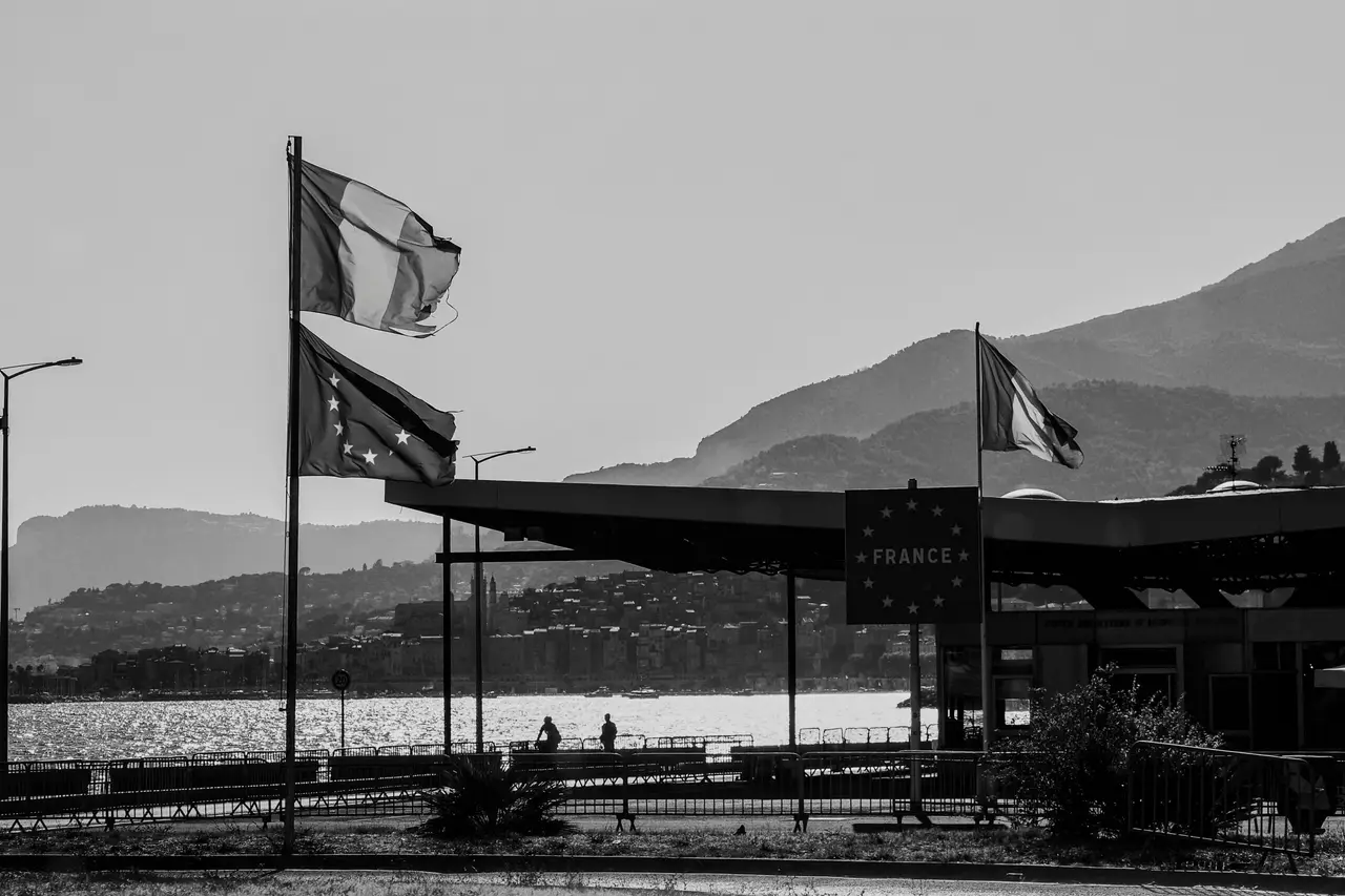 Black and white photo of a French border post with EU and French flag