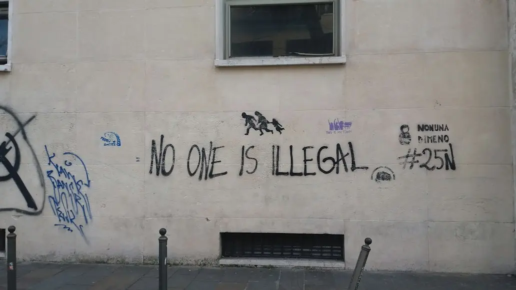 Beige wall with a writing "No one is illegal"