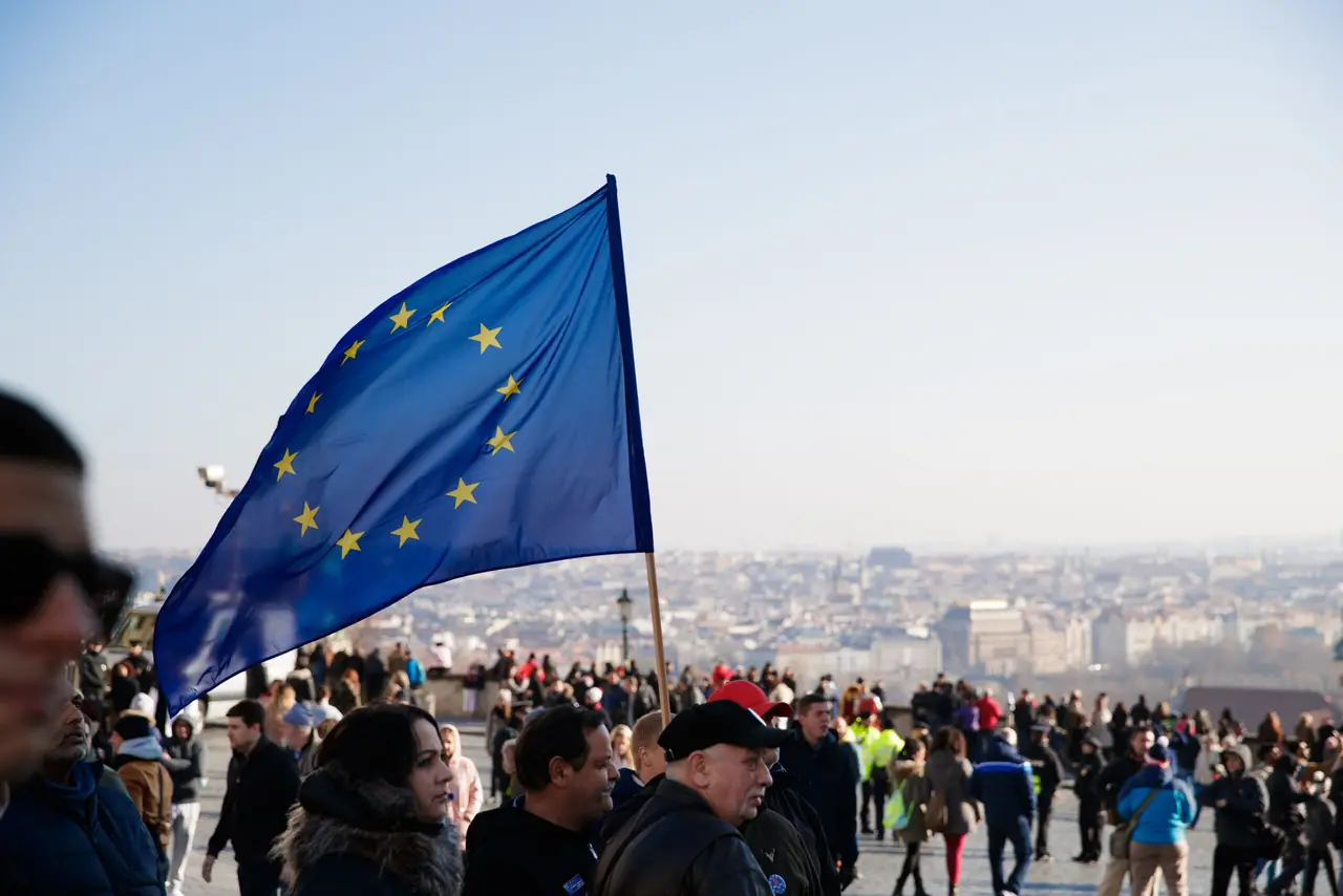 A European Union flag waving in the middle of a public square.