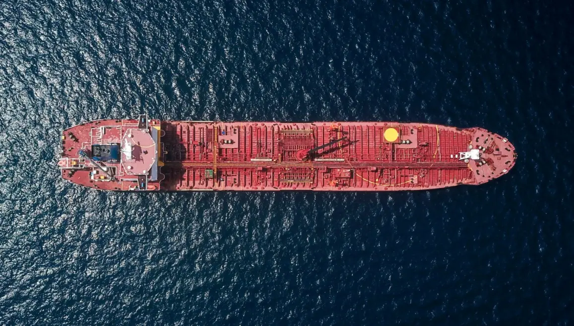 Aerial view of a red oil tanker sailing on dark blue sea
